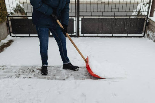 Person shoveling snow outside a house during winter