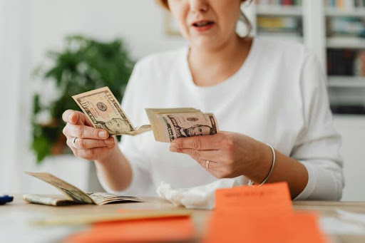 Woman counting dollar bills at a table