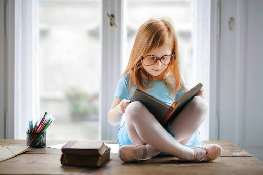 Young child reading a book while sitting on the floor
