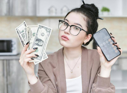 Woman holding dollar bills and a smartphone