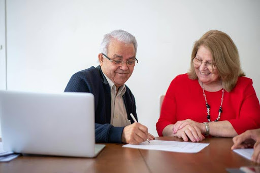 Two elderly people sitting together at a table, engaged in conversation.