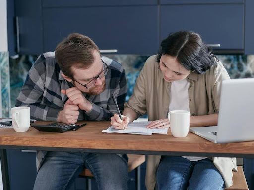 Two people sitting at a table filling out a financial form together