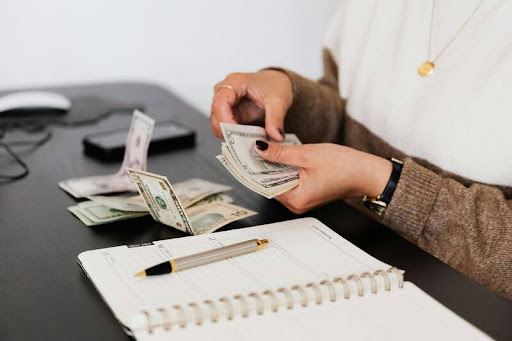 Person counting dollar bills at a desk