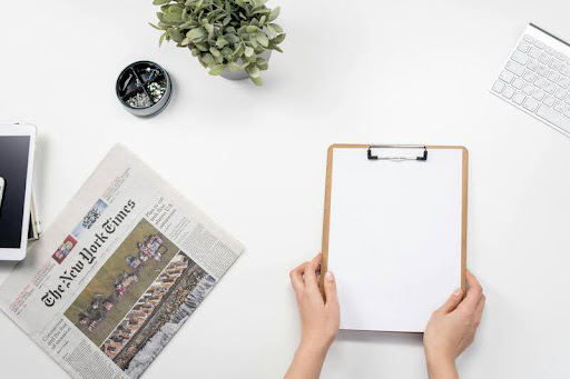 Clipboard and newspaper placed on a wooden table