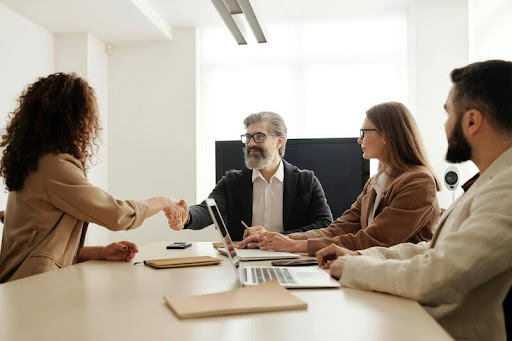 People in a modern office shaking hands during a job interview.