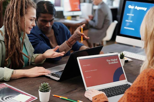 People sitting around a table with laptops engaged in a group learning session.