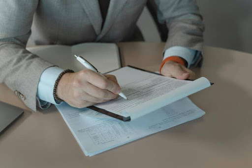 Person holding a financial document and pen at a table