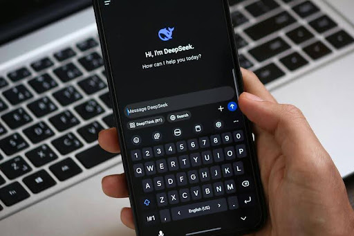 Person holding a smartphone displaying the DeepSeek AI assistant interface.