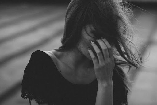 Woman covering her face with her hand, appearing stressed.