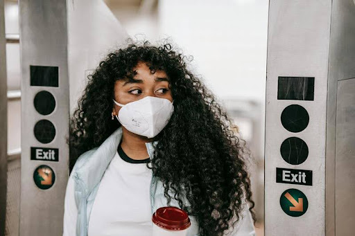 Woman wearing a face mask passing through an underground subway turnstile.
