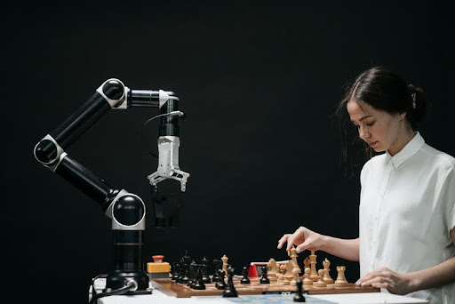 Woman in a white shirt playing chess against a robot.