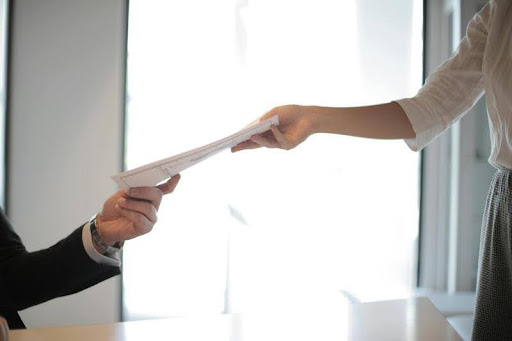 Job applicant handing over resume and cover letter to an interviewer.