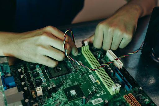 Closeup of a person repairing a motherboard with tangled wires