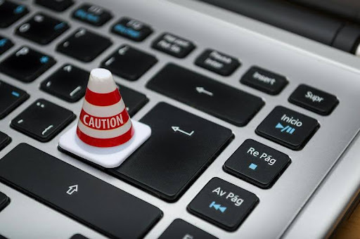 White caution cone placed on a computer keyboard symbolizing data security.