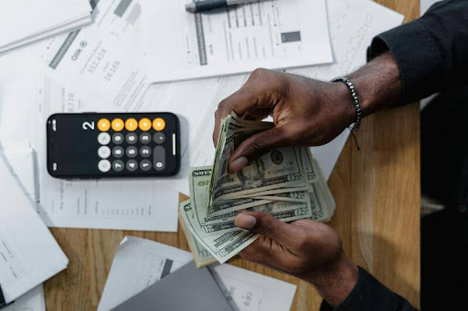 Person counting a stack of cash at a table
