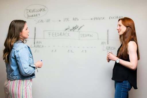 Two women presenting in front of a screen during a business meeting