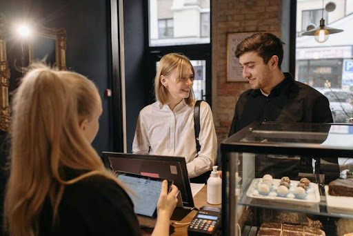 Customers browsing fresh pastries inside a local bakery shop.