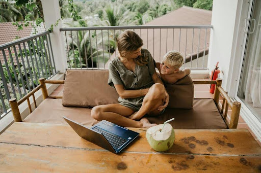 Woman talks to her son while working on a laptop at home