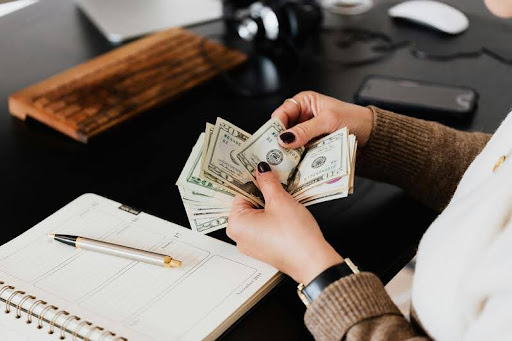 Woman counting dollar bills at a table