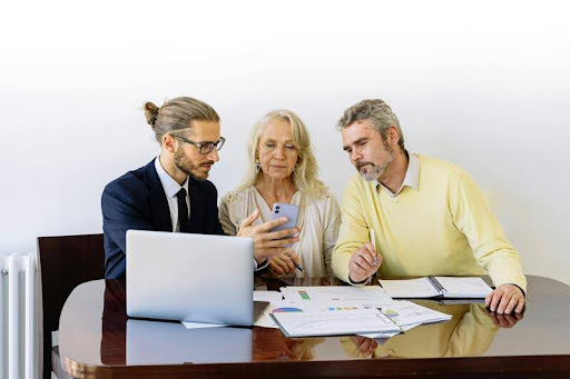 Three people sitting at a table working on a laptop