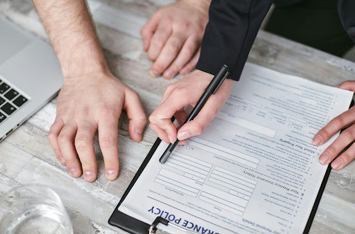 Person holding a pen and reviewing an insurance policy document