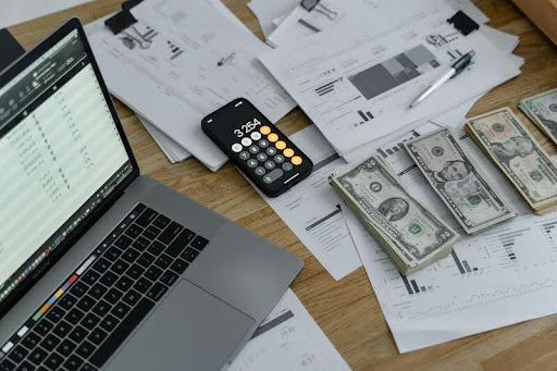 Laptop and smartphone on a wooden table displaying financial tools