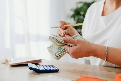 Woman counting dollar bills at a table