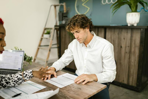 Man sitting at a table with a woman reviewing a document beside him