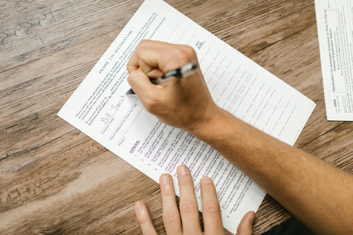 Person filling out a tax document with a pen at a table