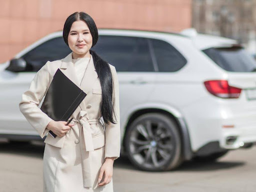 Woman standing next to a car holding a file folder