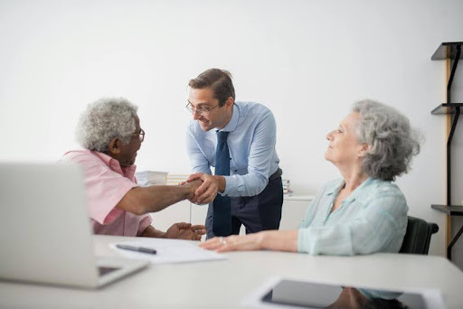 Elderly couple speaking with an insurance expert at a desk.