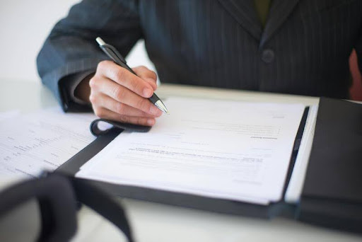 Person signing a renters insurance contract with a pen.