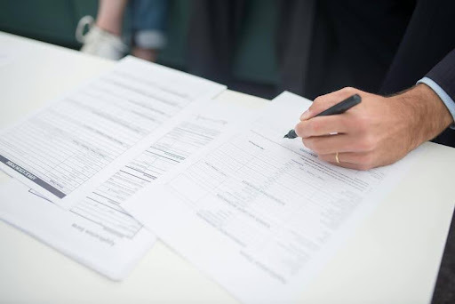 Person reviewing insurance documents with a pen in hand.