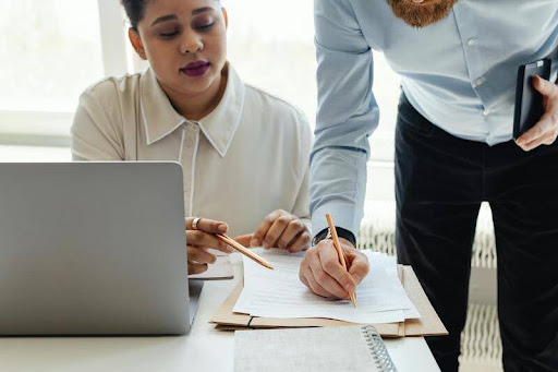 Man holding a pen talking to a woman across a desk