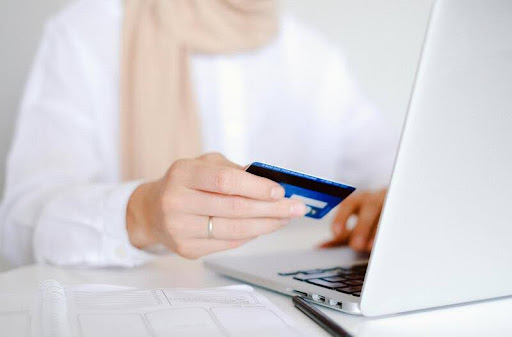 Woman holding a credit card while using a laptop