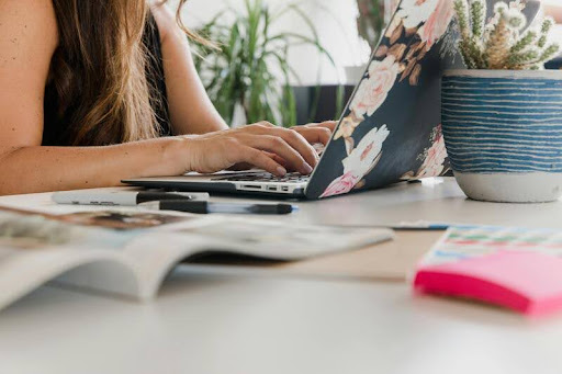 Woman using a laptop while writing on tax documents.
