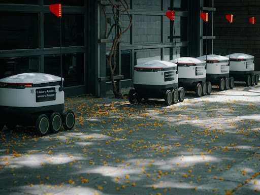Row of delivery robots parked along a city street.