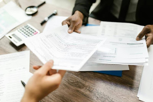 Person handing insurance documents to another person across a desk.
