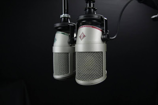 Two grey condenser microphones set up for a podcast recording.