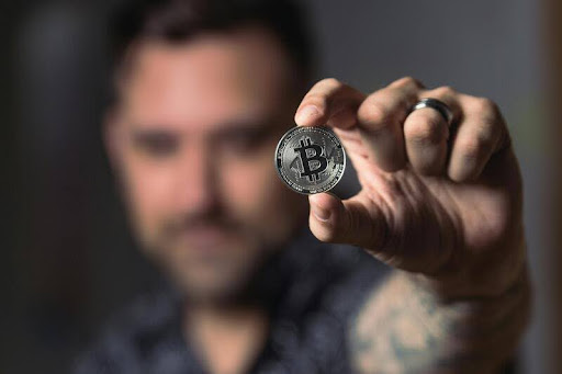 Person holding a physical Bitcoin coin in their hand.