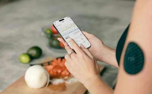 Woman checking her food tracking app on her smartphone with groceries on the kitchen counter.
