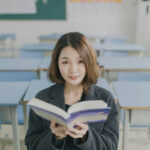 Student holding a book in a classroom, ready to learn