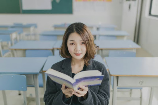 Student holding a book in a classroom, ready to learn