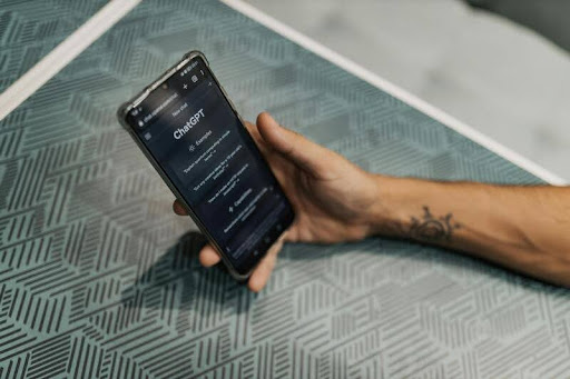 Man holding a smartphone displaying the ChatGPT interface.