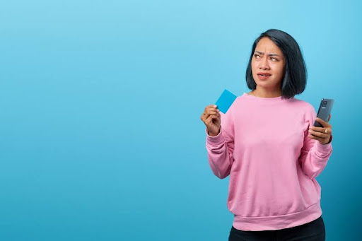 Woman checking her credit score on a phone while holding a credit card