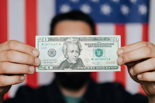 Man holding a $20 bill in his hand.