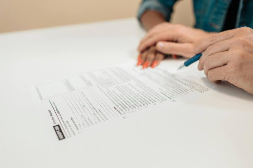 Two people writing on paper at a desk