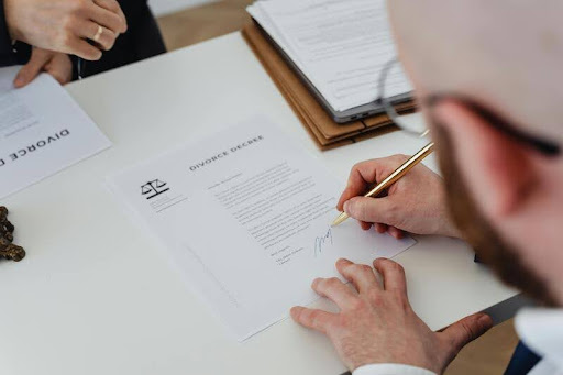 Person signing financial documents at a desk