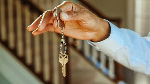 Hand holding silver house keys, symbolizing home ownership, trust, and a new beginning in real estate.