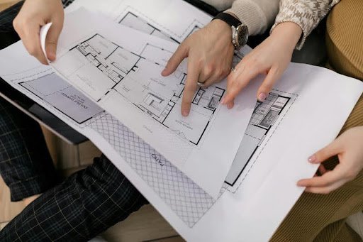 Hands holding architectural sketches of a modern house, highlighting design planning and construction concepts.